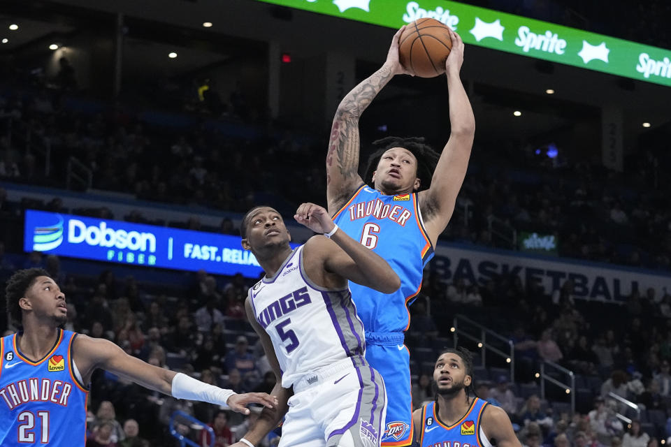 Oklahoma City Thunder forward Jaylin Williams (6) grabs a rebound behind Sacramento Kings guard De'Aaron Fox (5) in the first half of an NBA basketball game Sunday, Feb. 26, 2023, in Oklahoma City. (AP Photo/Sue Ogrocki)