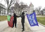 A supporter from Black Liberation, left, and one from the group "All Of Us' hold flags while counter protesting a Trump rally ahead of the inauguration of President-elect Joe Biden and Vice President-elect Kamala Harris at the New York state Capitol Sunday, Jan. 17, 2021, in Albany, N.Y. (AP Photo/Hans Pennink)