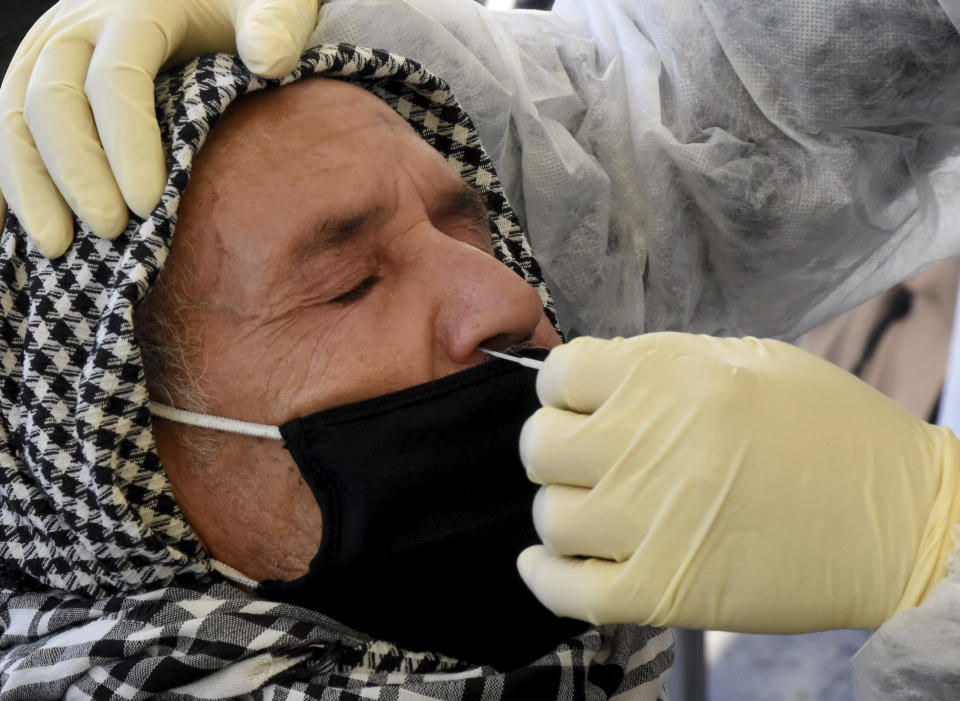 A medical technician collects a nasal swabs sample to test for COVID-19 at a mobile testing site in Tunis, Tunisia, Tuesday Dec.22, 2020. The World Health Organisation has cautioned against major alarm over a new, highly infectious variant of the coronavirus that has emerged in Britain, saying this was a normal part of a pandemic's evolution. (AP Photo/Hassene Dridi)