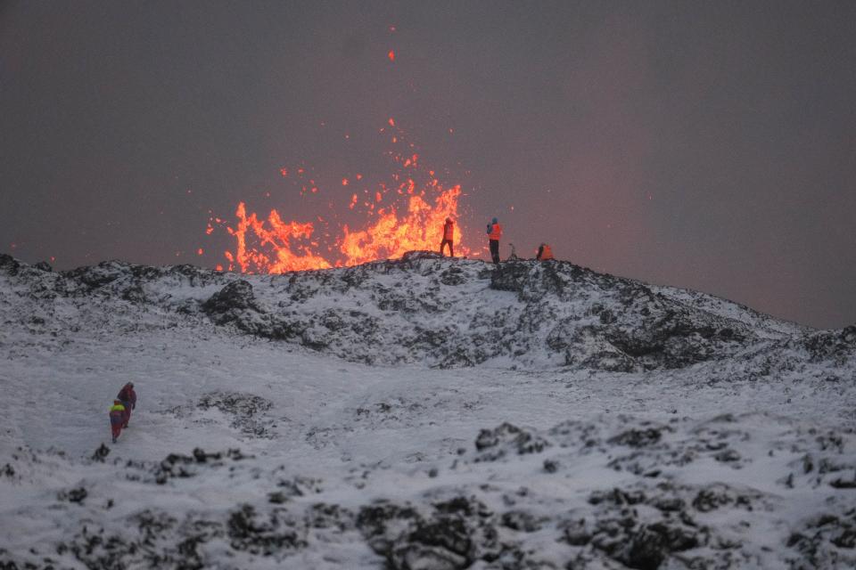 A team of scientists works on the ridge of a volcanic fissure as lava spews during a volcanic eruption (EPA)