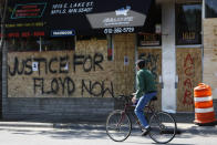 A man rides past Fiesta Mexicana Y Mas along Lake Street, Saturday, May 30, 2020, in Minneapolis. Outrage following the death of George Floyd, who died after being restrained by Minneapolis police officers on May 25, has led to the burning of businesses along the the Lake Street corridor where immigrants have found success. (AP Photo/Julio Cortez)