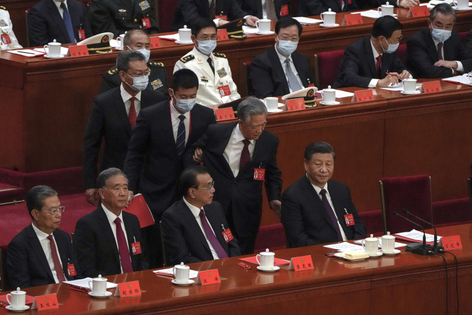 Former Chinese President Hu Jintao, front row second from right, talks to his predecessor as party leader Xi Jinping, right, as he is assisted to leave the hall during the closing ceremony of the 20th National Congress of China's ruling Communist Party at the Great Hall of the People in Beijing, Saturday, Oct. 22, 2022. (AP Photo/Andy Wong)