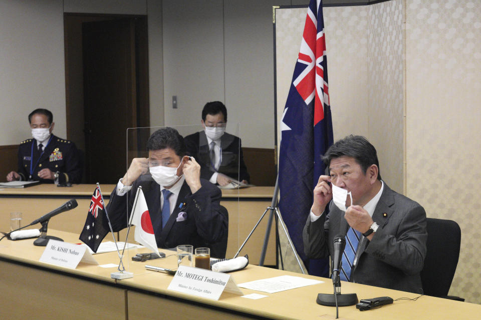 Japanese Foreign Minister Toshimitsu Motegi, right, and Defense Minister Nobuo Kishi, left, remove their protective masks as they attend a video conference with Australian Foreign Minister Marise Payne and Australian Defense Minister Peter Dutton, not in picture, at Foreign Ministry in Tokyo during their two-plus-two ministerial meeting Wednesday, June 9, 2021, in Tokyo. (AP Photo/Eugene Hoshiko, Pool)