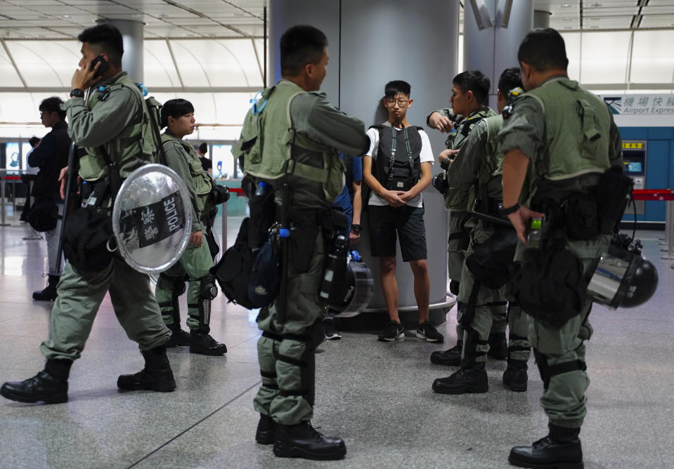 Riot police check a passenger's bag at the airport express station in downtown Hong Kong, Saturday, Sept. 7, 2019. Hong Kong authorities were limiting airport transport services and controlling access to terminals Saturday as they braced for a second weekend of disruption following overnight demonstrations that turned violent. (AP Photo/Vincent Yu)