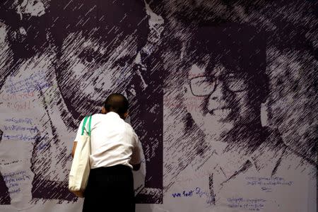 A man writes a goodwill message on a poster depicting detained Reuters reporters Wa Lone and Kyaw Soe Oo at an event discussing press freedom, in Yangon, Myanmar May 1, 2018. REUTERS/Ann Wang/Files