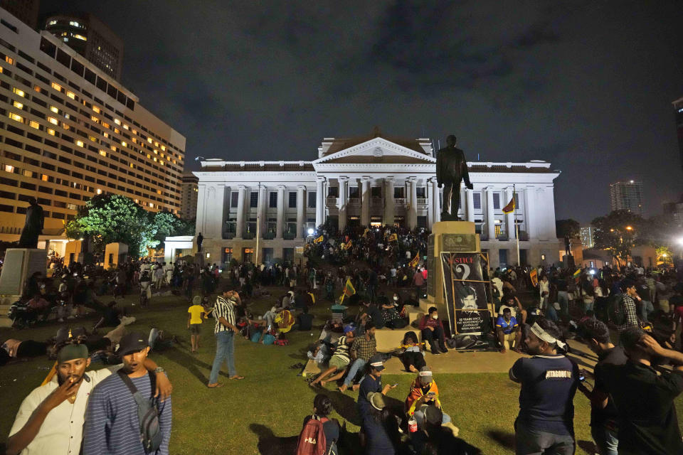 Protesters sit and walk around after storming in at the Sri Lankan president's office, in Colombo, Sri Lanka , Saturday, July, 9, 2022. Protesters have broken into the Sri Lankan prime minister's private residence and set it on fire, hours after he said he would resign when a new government is formed over a worsening economic crisis. It was the biggest day of demonstrations that also saw crowds storming the president's home and office. (AP Photo/ Eranga Jayawardena)