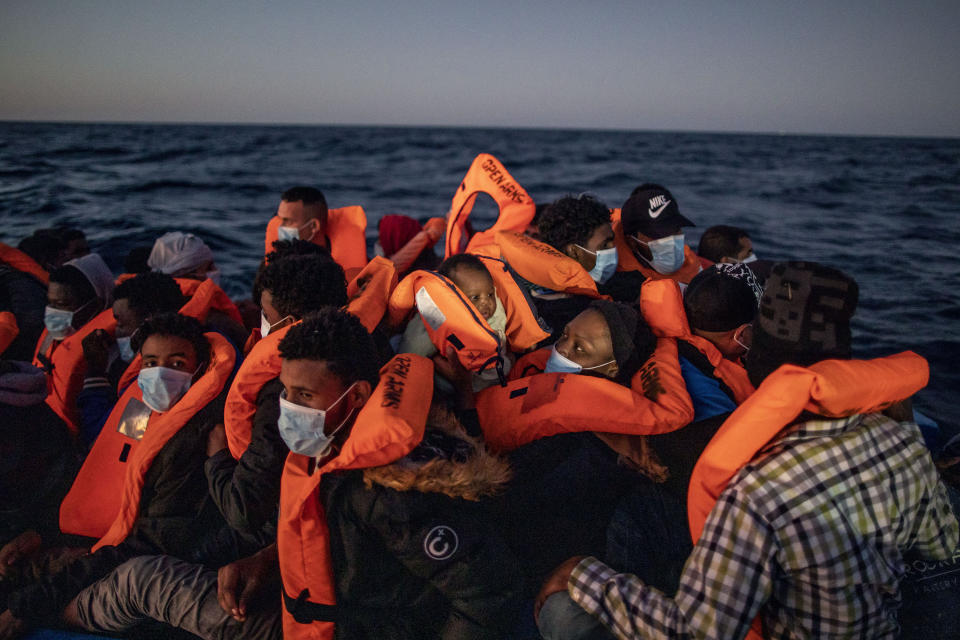 FILE - In this Friday, Feb 12, 2021 file photo, a woman holds a 3 month old baby as migrants and refugees from different African nationalities wait for assistance on an overcrowded rubber boat, as aid workers of the Spanish NGO Open Arms approach them in the Mediterranean Sea, international waters, at 122 miles off the Libyan coast. The U.N. migration agency says the number of migrants and refugees who died while attempting to reach Europe on dangerous sea routes more than doubled so far this year compared to the first six months of 2020. The International Organization for Migration said in a new report Wednesday, July 14, 2021 that at least 1,146 people perished between January and June. (AP Photo/Bruno Thevenin, File)