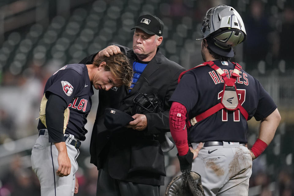 Home plate umpire Ted Barrett, middle, checks the hair of Cleveland Guardians relief pitcher James Karinchak for illegal substances during the eighth inning of the team's baseball game against the Minnesota Twins, Friday, Sept. 9, 2022, in Minneapolis. (AP Photo/Abbie Parr)