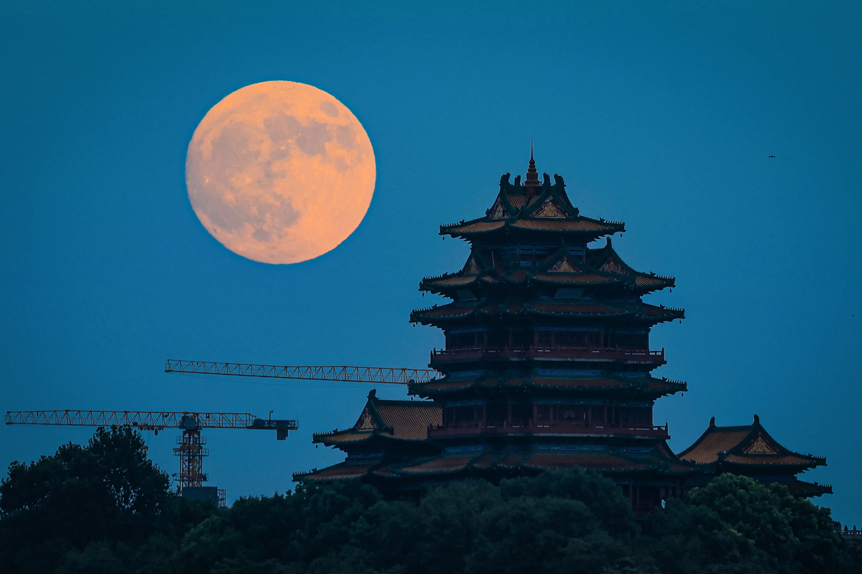 The full moon rises behind the Nanjing Yuejiang Tower in Nanjing, China on Tuesday.