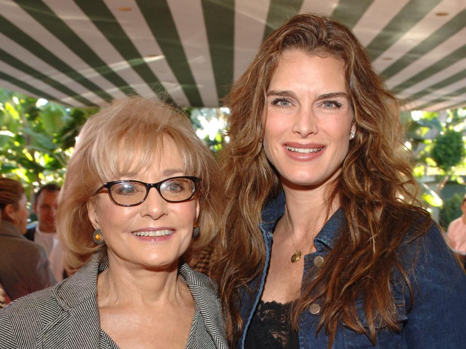 Two women, one with blonde hair and one with brown hair, face a camera