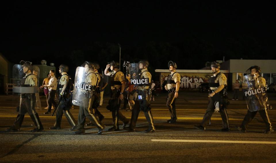 Police walk around protesters as people gather along West Florissant Avenue in Ferguson, Mo., Tuesday. (AP Photo/Jeff Roberson)