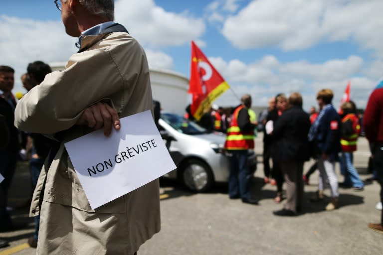 An Exxon employee holds a sign reading, "Non striker" as he stands near French CGT union members at the ExxonMobil oil refinery in Notre-Dame-de-Gravenchon, northwestern France, on May 24, 2016