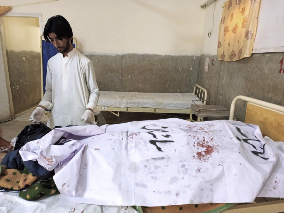 A paramedic stands beside a body of police officer, who was killed in a suicide bombing, at a hospital, in Sibi, a district in the Pakistan's Baluchistan province, Monday, March 6, 2023. A suicide bomber riding on a motorcycle rammed into a police truck in Pakistan's restive southwest, killing and wounding police officers in one of the deadliest attacks on security forces in recent months, authorities said. (AP Photo/Saeed-ud-Din)
