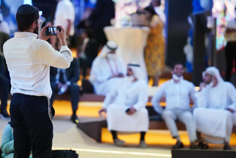 A man wearing a kippah bearing the tourist logo of the United Arab Emirates, takes a picture on his mobile phone at the Israeli pavilion at Expo 2020 in Dubai, United Arab Emirates, Thursday, Oct. 7, 2021. Israel ceremonially opened its gleaming pavilion at the world's fair in Dubai on Thursday, over a year after normalizing ties with the United Arab Emirates and amid a pandemic that has disrupted much of the tourist and cultural exchanges promised by the U.S.-brokered accords. (AP Photo/Jon Gambrell)