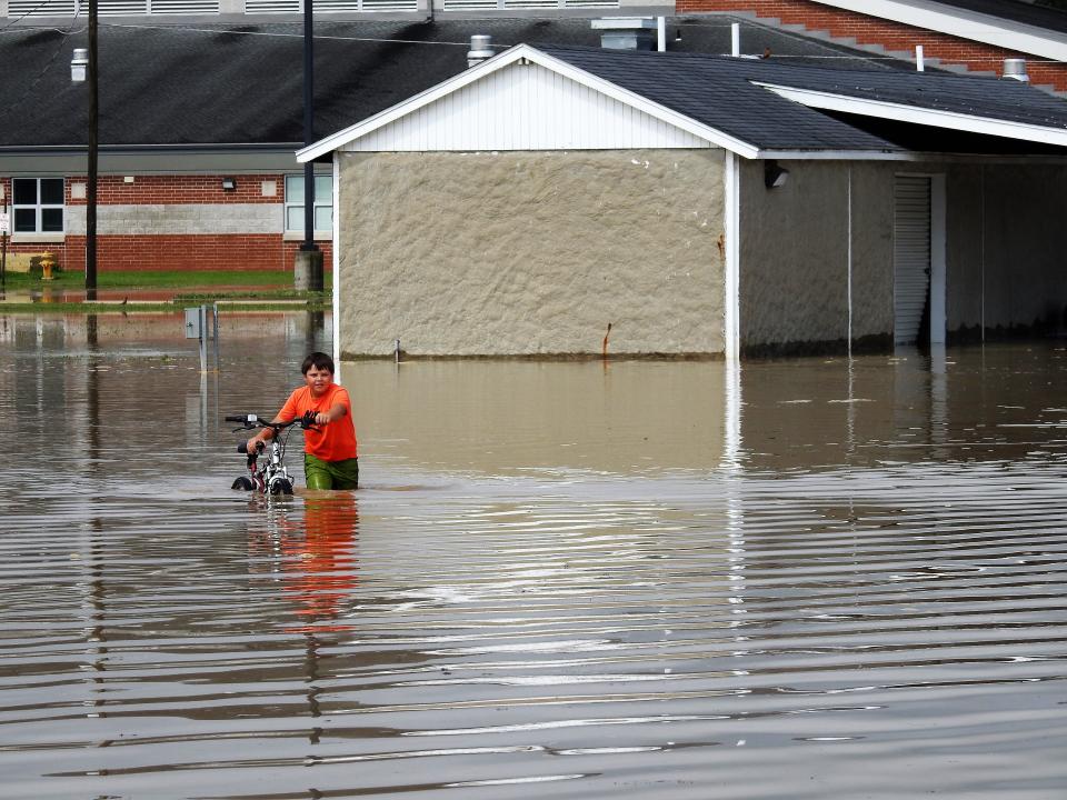 Sebastian Calvo, then 9, pushed his bicycle through flood waters behind Ridgewood Middle School in West Lafayette in June 2019. The event showed many how Coshocton residents pull together and take care of their own in times of crisis.