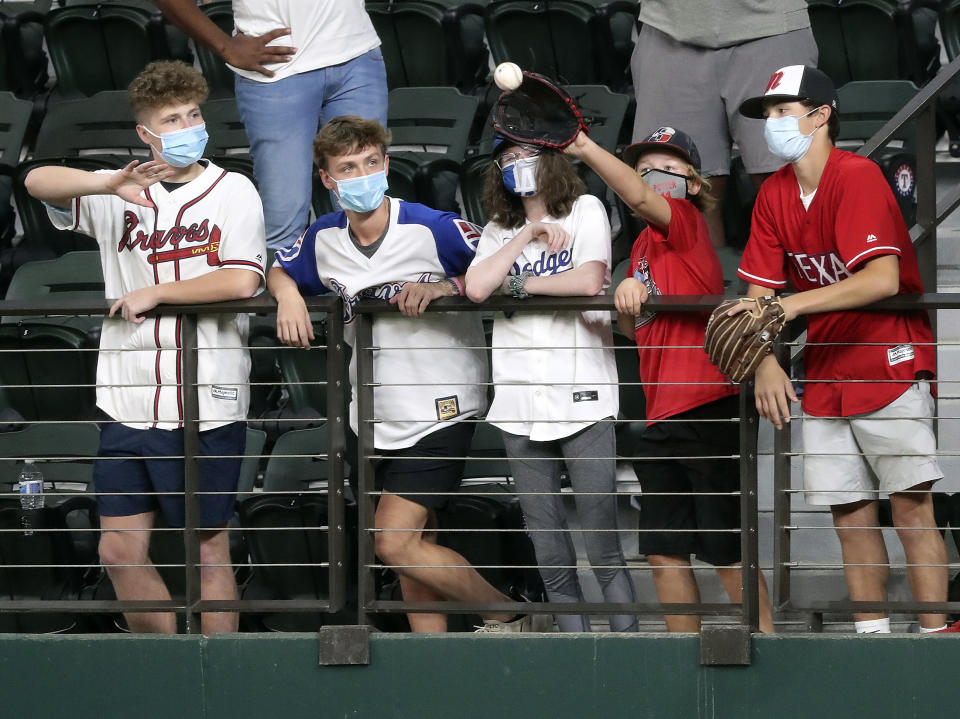 Fans in center field catch home run balls while the Atlanta Braves take batting practice before playing the Los Angeles Dodgers in Game 1 of a baseball National League Championship Series, Monday, Oct. 12, 2020, in Arlington, Texas. (Curtis Compton/Atlanta Journal-Constitution via AP)