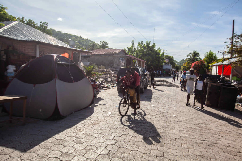 Kids ride a bike past a tent improvised as a shelter after a 7.2-magnitude earthquake struck Haiti on August 16, 2021 in Corvalion, Les Cayes, Haiti. (Photo by Richard Pierrin/Getty Images)