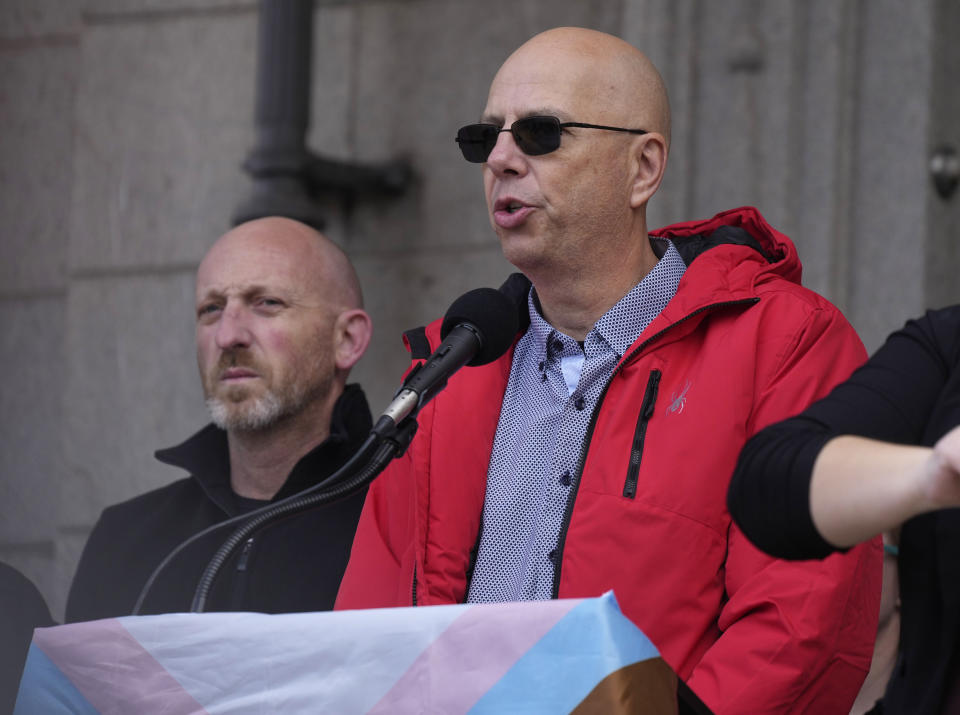 Co-owners of Club Q, Matthew Haynes, front, and Nic Grzecka, address the crowd after a 25-foot historic pride flag was displayed on the exterior of City Hall to mark the weekend mass shooting at the gay nightclub Wednesday, Nov. 23, 2022, in Colorado Springs, Colo. The flag, known as Section 93 of the Sea to Sea Flag, is on loan for two weeks to Colorado Springs from the Sacred Cloth Project. (AP Photo/David Zalubowski)
