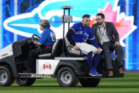 Toronto Blue Jays center fielder George Springer is taken out of the game on a cart after he collided with shortstop Bo Bichette while to trying to catch a ball hit by Seattle Mariners J.P. Crawford during the eighth inning of Game 2 of a baseball AL wild-card playoff series Saturday, Oct. 8, 2022, in Toronto. (Frank Gunn/The Canadian Press via AP)