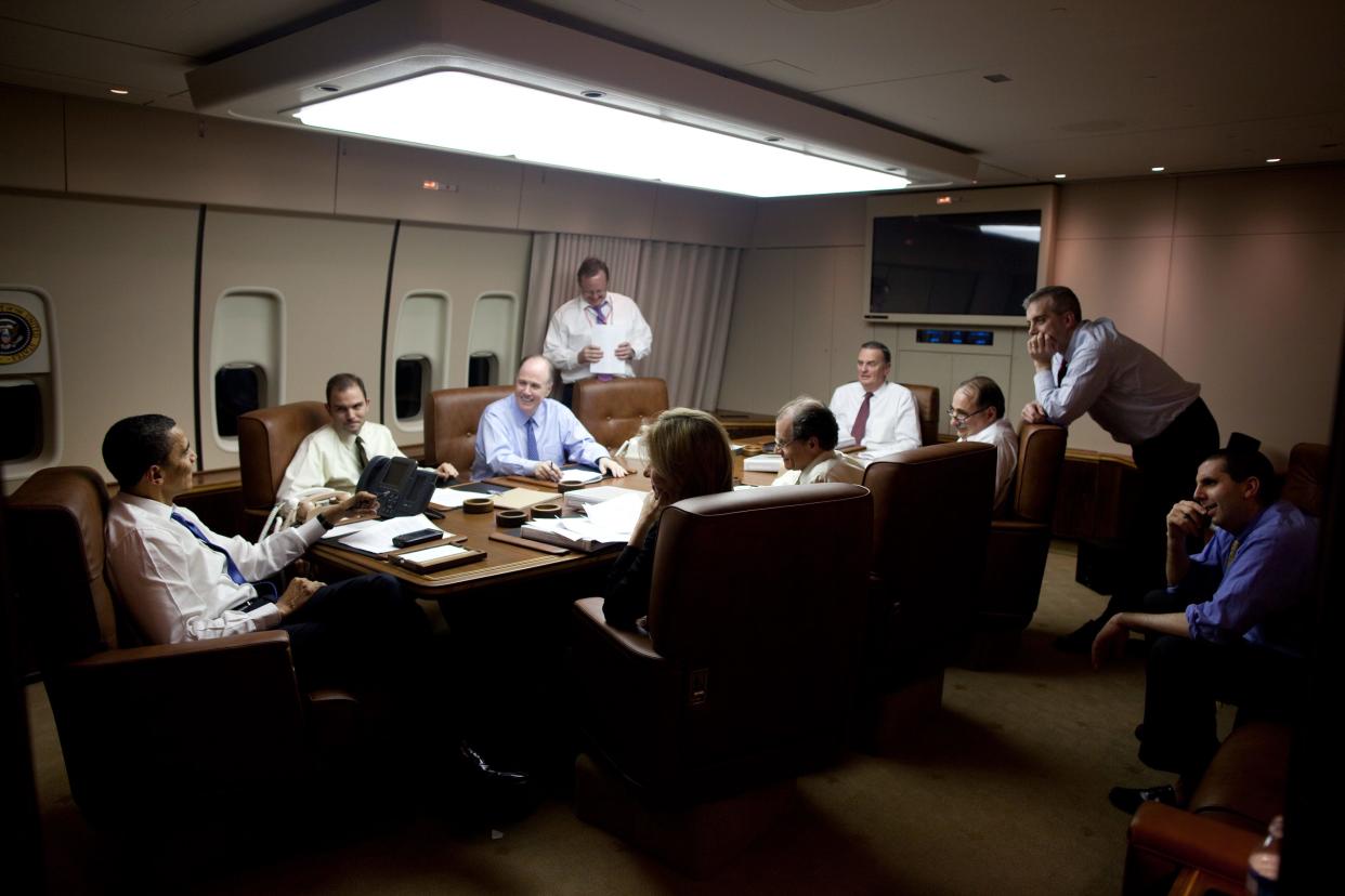 Barack Obama sits around a table with staff on Air Force One