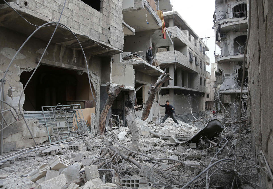 <p>A Syrian youth checks the site of Syrian government bombardments in Hamouria, in the besieged eastern Ghouta region on the outskirts of the capital Damascus on Feb. 22, 2018. (Photo: Abdulmonam Eassa /AFP/Getty Images) </p>