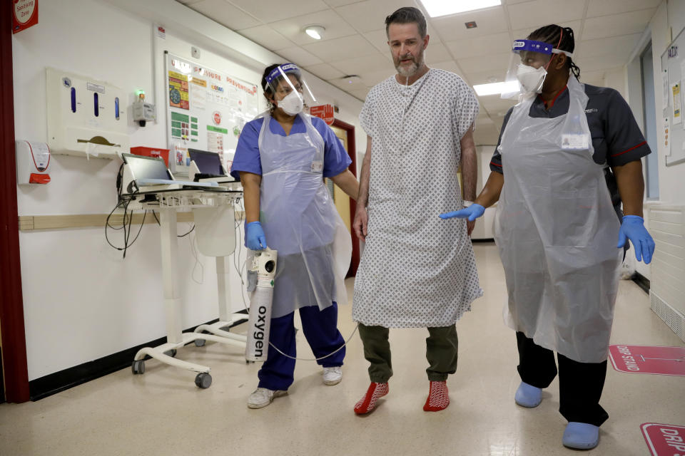 Felicia Kwaku, Associate Director of Nursing, right, and Anna Castellano, Matron, left, help COVID-19 patient Justin Fleming walk again after recovering, on the Cotton ward at King's College Hospital in London, Wednesday, Jan. 27, 2021. Fleming is one of more than 37,000 coronavirus patients being treated now in Britain's hospitals, almost double the number of the spring surge. King's College Hospital, which sits in a diverse, densely populated area of south London, had almost 800 COVID-19 patients earlier this winter. (AP Photo/Kirsty Wigglesworth, pool)