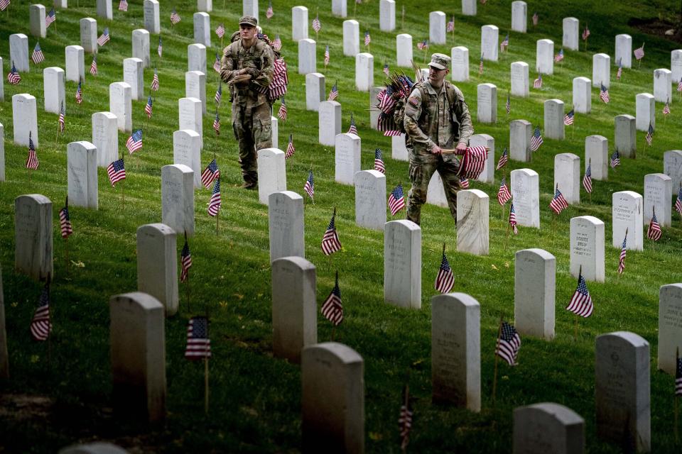 Members of the 3rd U.S. Infantry Regiment also known as The Old Guard place flags in front of each headstone for "Flags-In" at Arlington National Cemetery in Arlington, Thursday, May 25, 2023, to honor the Nation's fallen military heroes ahead of Memorial Day. (AP Photo/Andrew Harnik)