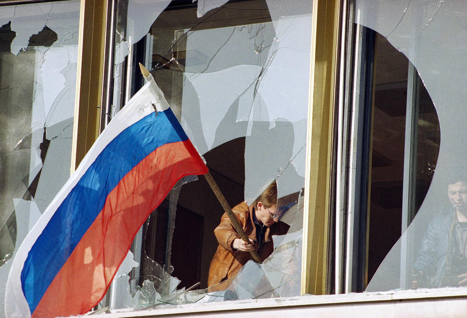 FILE - A Muscovite celebrates the victory of forces loyal to Yeltsin by sticking the Russian flag through a smashed window of Russia's parliament in Moscow, on Oct. 4, 1993. Hard-line lawmakers surrendered to the Russian Army. The October 1993 violent showdown between the Kremlin and supporters of the rebellious parliament marked a watershed in Russia's post-Soviet history. (AP Photo/Alexander Zemlianichenko, File)