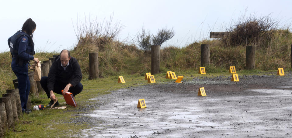 Police collect and photograph evidence in the carpark of the Te Toto Gorge lookout on Whaanga Rd, south of Raglan, New Zealand, Friday, Aug. 16, 2019. A manhunt was underway in New Zealand after an Australian tourist was killed following what police believe was a random attack on the van that he and his partner were sleeping inside. (Alan Gibson/New Zealand Herald via AP)