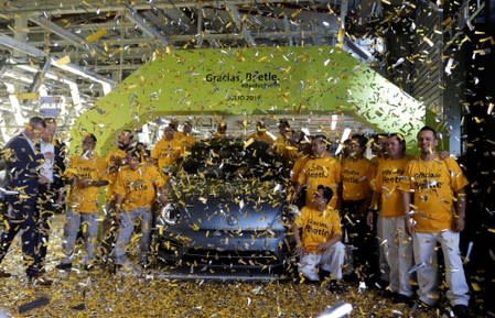 Employees pose for a picture next to a Volkswagen Beetle car during a ceremony marking the end of production of VW Beetle cars, at company's assembly plant in Puebla