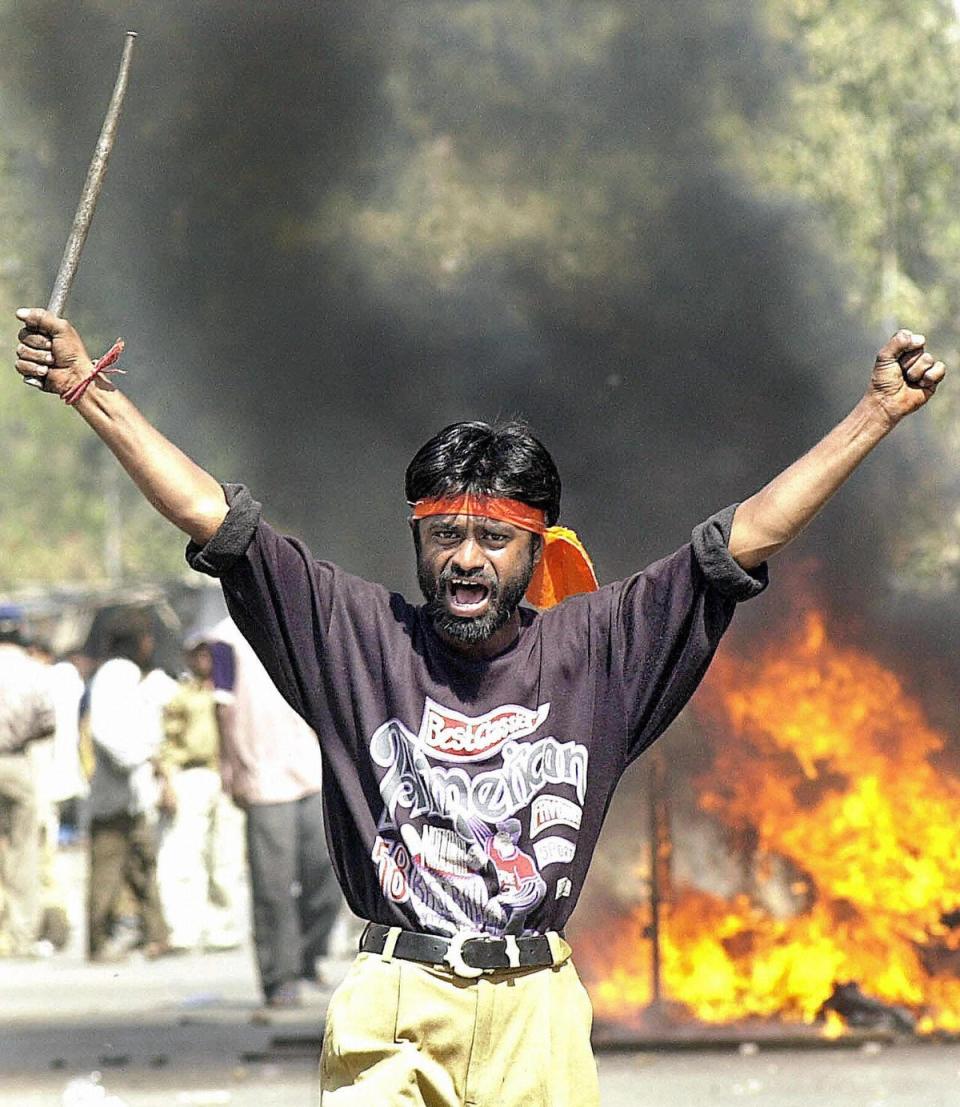 This picture taken 28 February 2002 shows a Bajranj Dal activist armed with a iron stick shouting slogans as a mob burned Muslim shops and attacked residences at Sahapur in Ahmedabad (Getty Images)