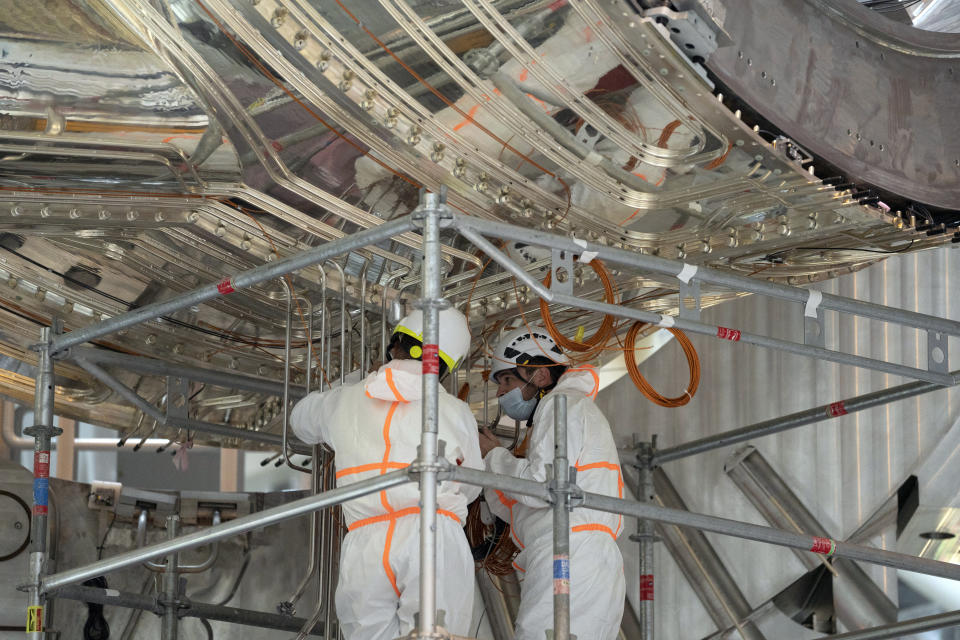 Workers inspect components of the ITER machine at the Tokamak complex in Saint-Paul-Lez-Durance, France, Thursday, Sept. 9, 2021. Scientists at the International Thermonuclear Experimental Reactor in southern France took delivery of the first part of a massive magnet so strong its American manufacturer claims it can lift an aircraft carrier. (AP Photo/Daniel Cole)