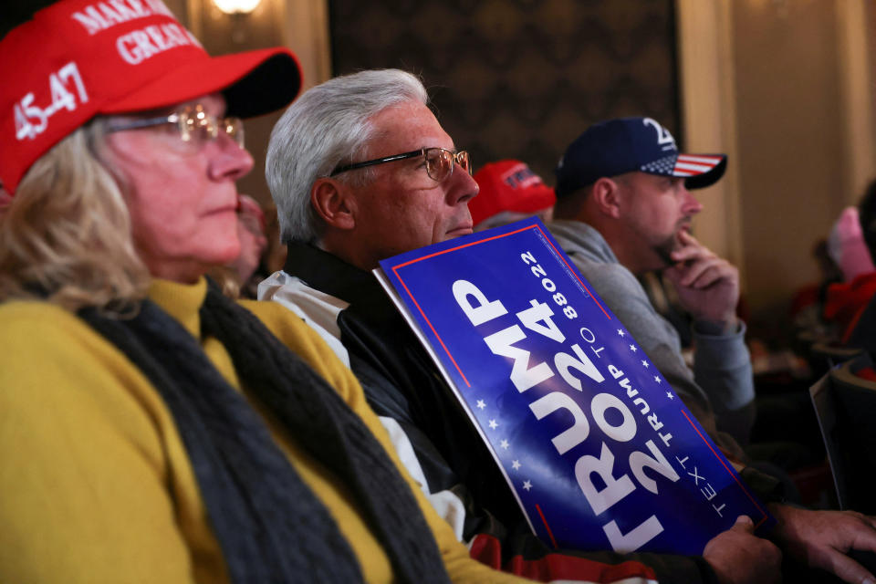 Supporters of Trump sitting at a rally listen to him speak.