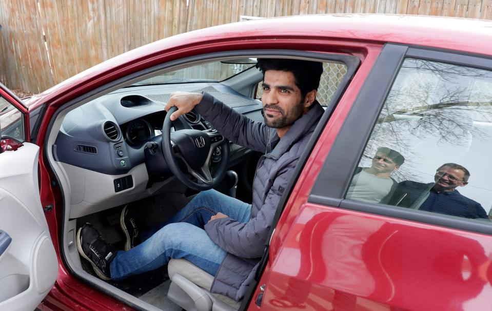 After receiving his driver's license earlier in the year, Ahmad Samim Samimi tests out a vehicle for sale while talking to Fayaz Nabizada and Mike Ruminski on April 10, 2022, in the Green Bay-area village of Allouez. Transportation “is a critical need for people trying to become self-sufficient,” says Ruminski, who has helped local Afghan evacuees obtain driver’s licenses, enroll in English classes and connect with job specialists.