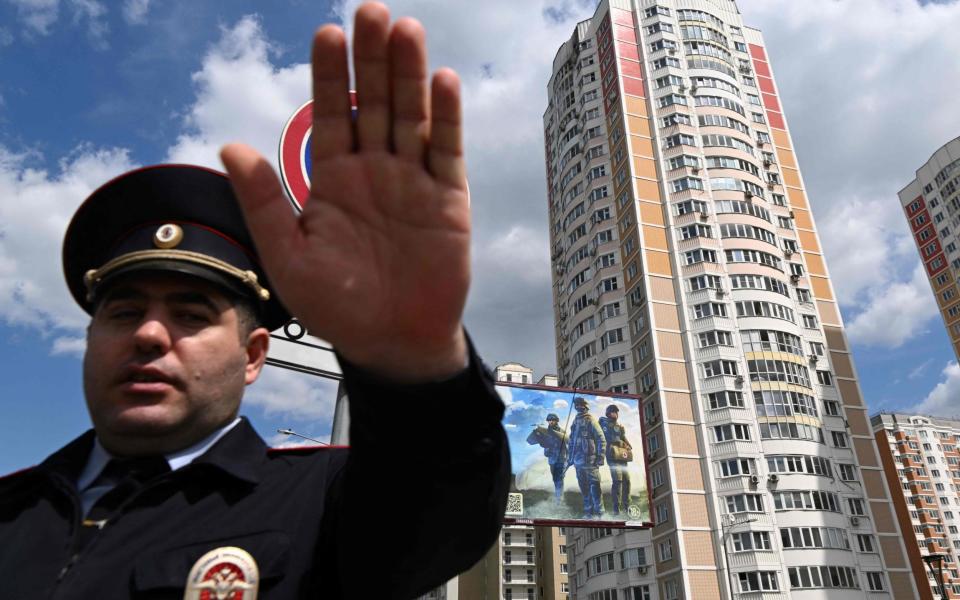 A police officer secures an area outside a damaged multi-storey apartment building after a reported drone attack in Moscow