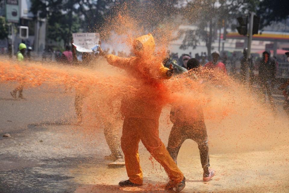 Police spray a water canon at protesters (AP)