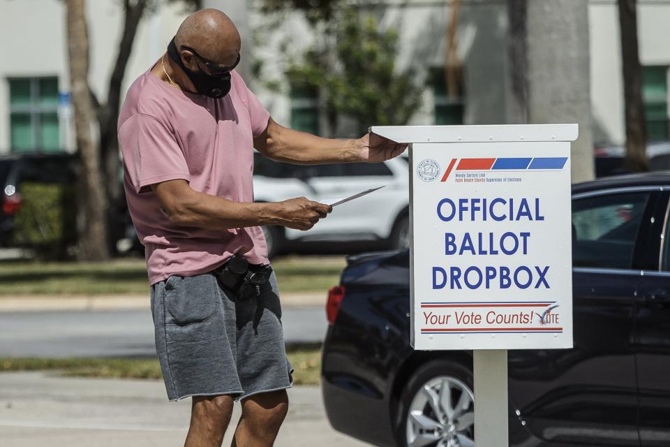 A voter deposits a mail ballot into an official drop box at the Palm Beach County Supervisor of Elections office in unincorporated Palm Beach County, Fla., on Tuesday, March 9, 2021.
