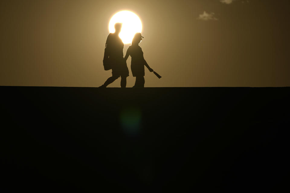 FILE - People walk along a trail as the sun sets, on July 16, 2023, in Death Valley National Park, Calif. The death certificates of more than 2,300 people who died in the United States last summer mention the effects of excessive heat, the highest number in 45 years of records, according to an Associated Press analysis of Centers for Disease Control and Prevention data. With May already breaking heat records, 2024 could be even deadlier. (AP Photo/John Locher, File)