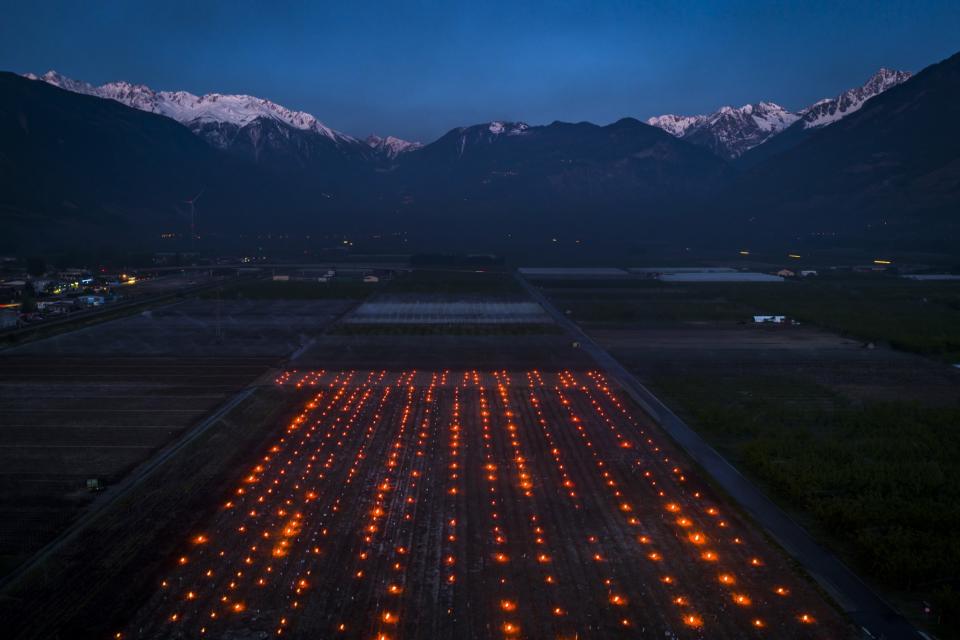 <p>Anti-frost candles burn in a vineyard in the middle of the Swiss Alps. Due to unusually low temperatures wine growers try to protect their grape shoots with anti-frost candles. (Valentin Flauraud/Keystone via AP) </p>