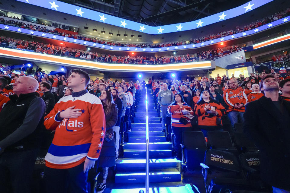 FILE - Fans stand for the national anthem in the Capital One Arena before an NHL hockey game between the Washington Capitals and the New Jersey Devils, Tuesday, Feb. 20, 2024, in Washington. The NBA’s Washington Wizards and NHL’s Washington Capitals are staying in the District of Columbia. Owner Ted Leonsis and Mayor Muriel Bowser announced the development at a news conference at Capital One Arena on Wednesday, March 27, 2024. (AP Photo/Alex Brandon, File)