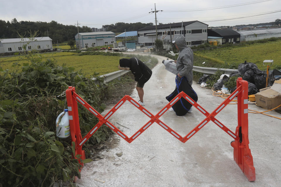 A quarantine official, right, sprays disinfectant solution to a man as a precaution against African swine fever near a pig farm in Paju, South Korea, Friday, Sept. 20, 2019. South Korea said Friday that it is investigating two more suspected cases of African swine fever from farms near its border with North Korea, as fears grow over the spread of the illness that has decimated pig herds across Asia. (AP Photo/Ahn Young-joon)