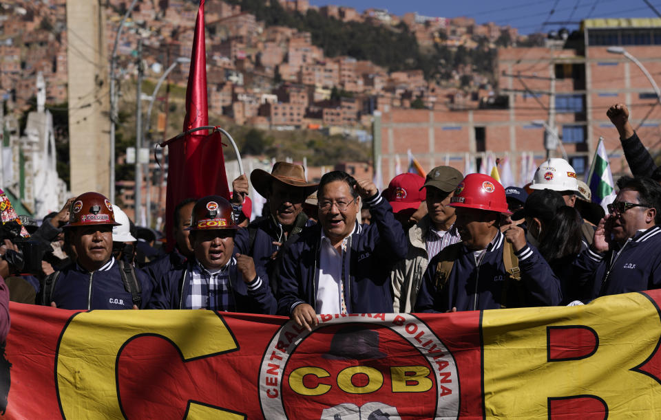 El presidente boliviano Luis Arce, en el centro, grita consignas durante la marcha del Día del Trabajo en La Paz, el lunes 1 de mayo de 2023. El segundo desde la izquierda es Juan Carlos Huarachi, líder del principal sindicato del país. (AP Foto/Juan Karita)