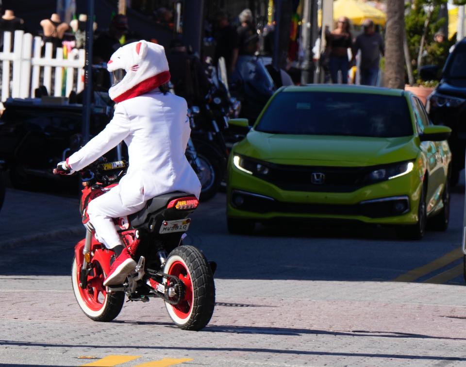 Scott Fitzgerald, adorned in a white suit and cat-themed helmet, rides his Honda Glom sport motorcycle along Main Street on the opening day of Biketoberfest. The four-day event runs through Sunday in Daytona Beach.