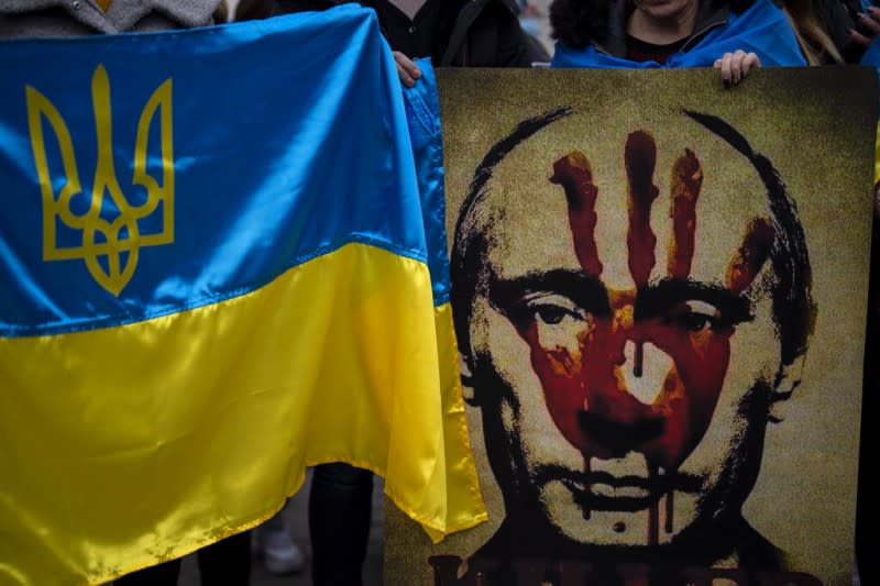 普京下令入侵烏克蘭之後，歐美各地出現許多反對戰爭的人潮，許多抗議者都高舉普京的肖像與烏克蘭國旗。（美聯社）