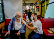 An 85-year-old man receives a booster vaccination in the so called "vaccination express" tram in central Frankfurt, Thursday, Nov. 4, 2021. About 100 people are vaccinated every day in two trams. (AP Photo/Michael Probst)