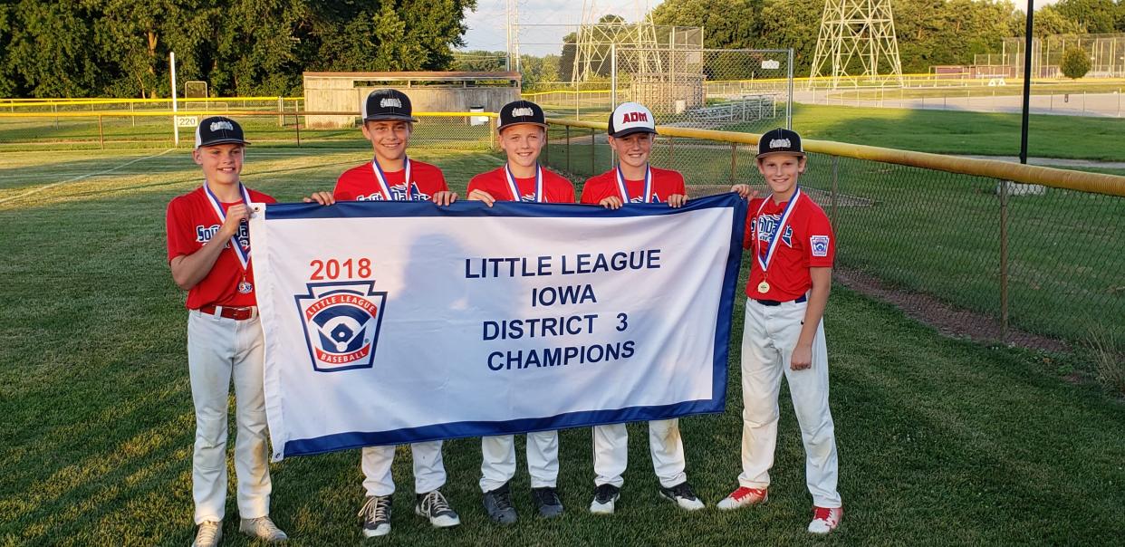 Aiden Flora (left) and Brevin Doll (center) pose with a Little League district championship banner. Flora and Doll competed in various sports together, including football and track.