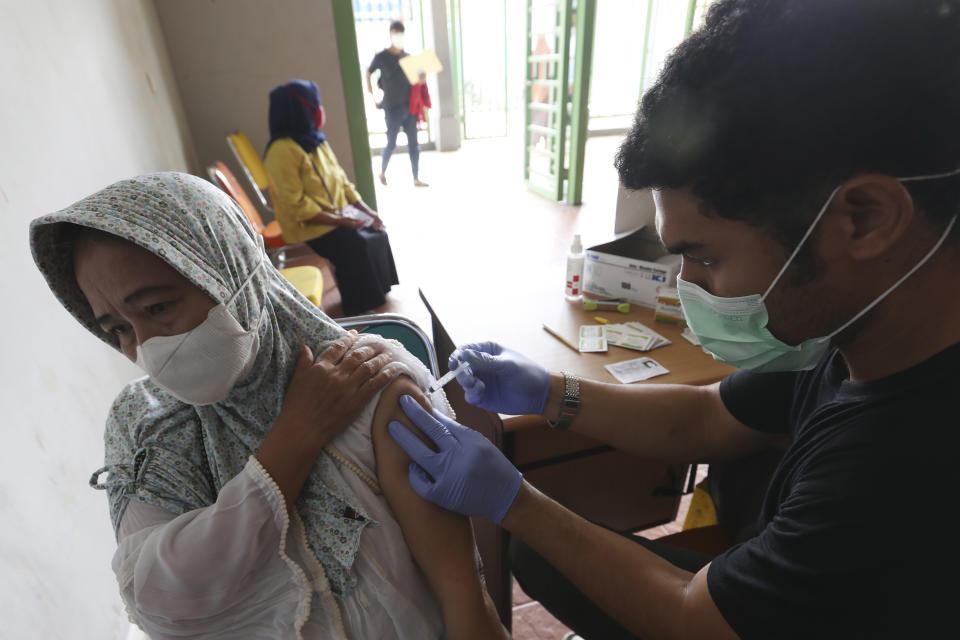 A woman receives a shot of the AstraZeneca COVID-19 vaccine during a vaccination campaign at the Patriot Candrabhaga Stadium in Bekasi on the outskirts of Jakarta, Indonesia Friday, Nov. 26, 2021. Indonesia has significantly recovered from a mid-year spike in coronavirus cases and deaths that was one of the worst in the region, but with its vaccination drive stalling and holidays approaching, experts and officials warn the island nation could be set soon for another surge. (AP Photo/Achmad Ibrahim)