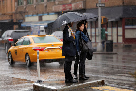 Pedestrians wait to cross a street during a rain shower in New York, U.S., March 1, 2017. REUTERS/Lucas Jackson