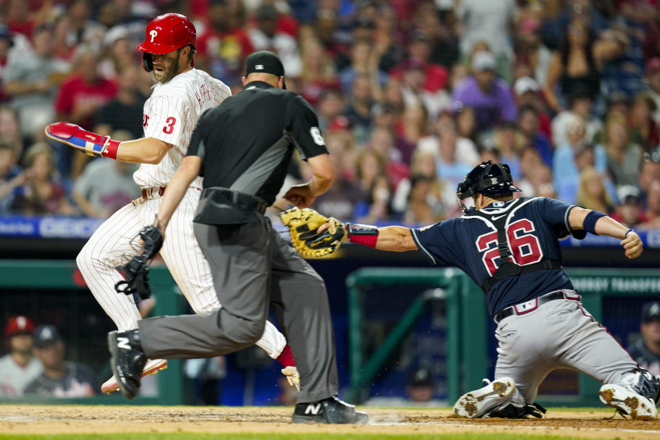 Philadelphia Phillies' Bryce Harper, left, scores a run as he gets past the tag by Atlanta Braves catcher Stephen Vogt, right, during the fifth inning of a baseball game, Friday, July 23, 2021, in Philadelphia. (AP Photo/Chris Szagola)