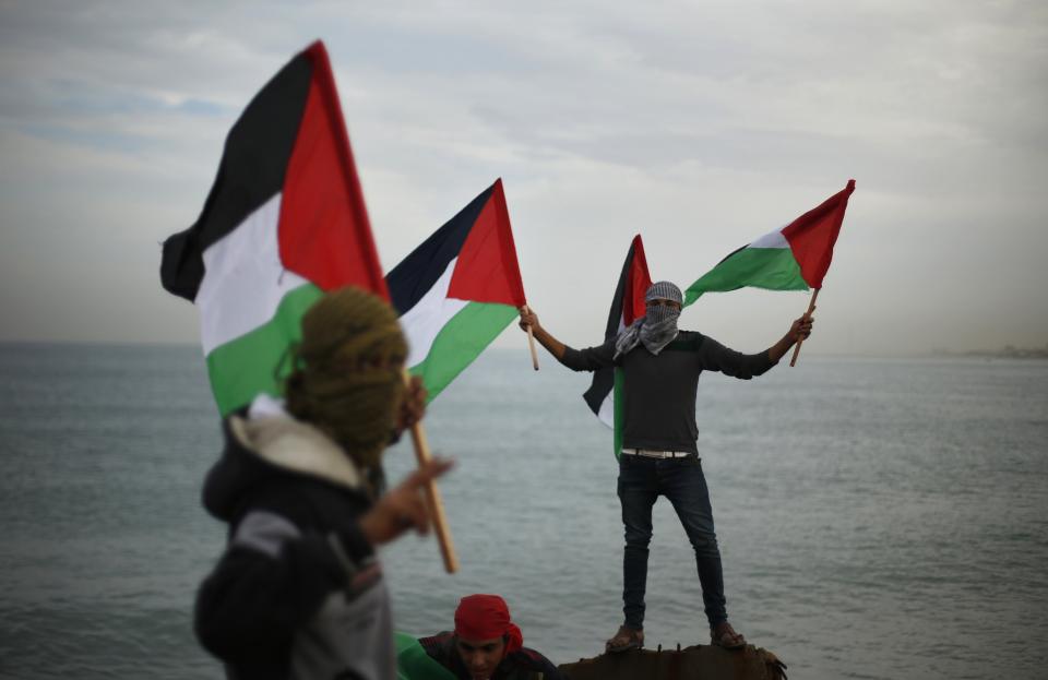 Palestinians wave national flags during a protest against the blockade on Gaza, at the seaport of Gaza City